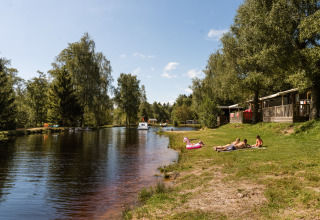 Parque vacacional Flower Camping La Sténiole en Grand Est, Francia, con gente descansando junto al lago.