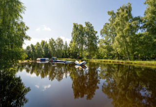 Peaceful lake with inflatable obstacles surrounded by trees at Flower Camping La Sténiole, Grand Est, France.