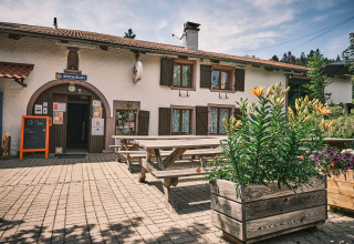 Outdoor seating with wooden benches and flower boxes at a restaurant in Flower Camping La Sténiole, Grand Est, France.