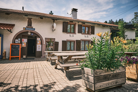 Buiten zitgedeelte met houten banken en bloembakken bij een restaurant op Flower Camping La Sténiole in Frankrijk.
