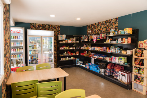 Kleine winkel met rekken vol snacks en drankjes bij Flower Camping La Sténiole, Grand Est, Frankrijk.