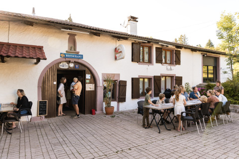 Gäste essen im Freien vor einem Restaurant im Flower Camping La Sténiole in Grand Est, Frankreich.