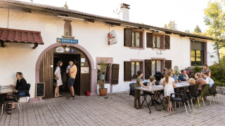 Familier nyder middag udenfor en restaurant på Flower Camping La Sténiole feriepark i Grand Est, Frankrig.