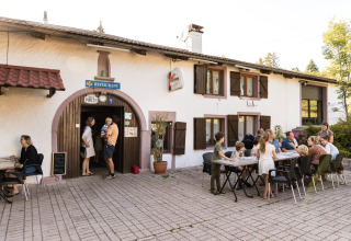 Familier nyder middag udenfor en restaurant på Flower Camping La Sténiole feriepark i Grand Est, Frankrig.
