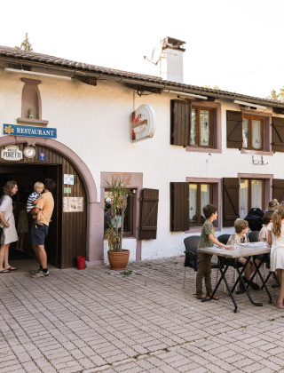 Familias cenando al aire libre en un restaurante del Flower Camping La Sténiole en Grand Est, Francia.