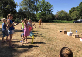 Kinder spielen Bogenschießen im Freien im Flower Camping La Sténiole, Grand Est, Frankreich, an einem sonnigen Tag.