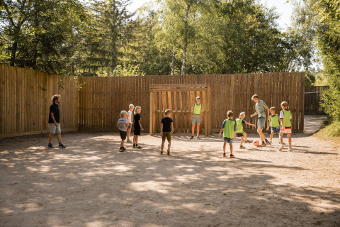 Kinder spielen Fußball im Freien bei schönem Wetter im Flower Camping La Sténiole, Grand Est, Frankreich.