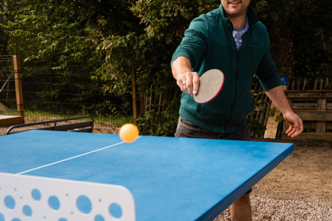 Mann spielt Tischtennis im Freien im Flower Camping La Sténiole, einem Ferienpark in Grand Est, Frankreich.