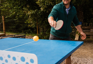 Uomo che gioca a ping pong all'aperto presso Flower Camping La Sténiole, villaggio vacanze in Grand Est, Francia.