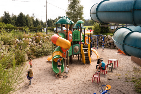Kinder spielen auf einem bunten Spielplatz mit Rutschen im Flower Camping La Sténiole in Grand Est, Frankreich.