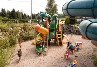 Bambini giocano su un colorato parco giochi con scivoli al Flower Camping La Sténiole, Grand Est, Francia.