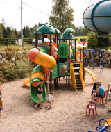 Niños juegan en un colorido parque infantil con toboganes en Flower Camping La Sténiole en Grand Est, Francia.