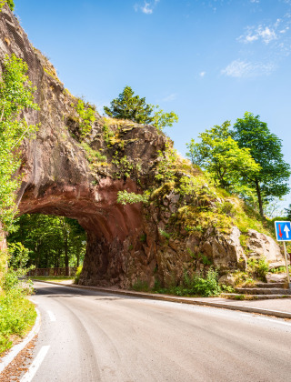 Naturskønt vejstræk i nærheden af Granges-Aumontzey, Grand Est, Frankrig, med vej gennem klippebue.