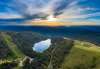 Panoramisk udsigt over bjerge, søer og skove nær Granges-Aumontzey i Grand Est-regionen, Frankrig ved solnedgang.