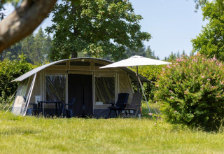Großes Zelt mit Gartenmöbeln und Sonnenschirm im Grünen bei Auf Kengert Lodge in Luxemburg im Sommer.