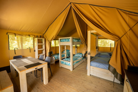Indvendig udsigt over en safari-telt på Flower Camping La Sténiole i Frankrig med senge og spisebord.