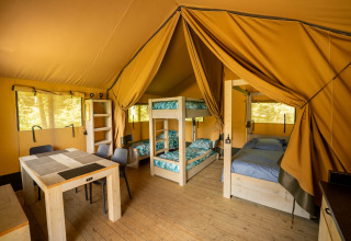 Indvendig udsigt over en safari-telt på Flower Camping La Sténiole i Frankrig med senge og spisebord.