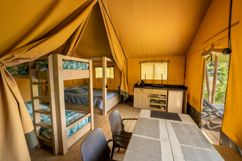 Indvendig udsigt over Tente safari hos Flower Camping La Sténiole i Frankrig med køjesenge og køkken.