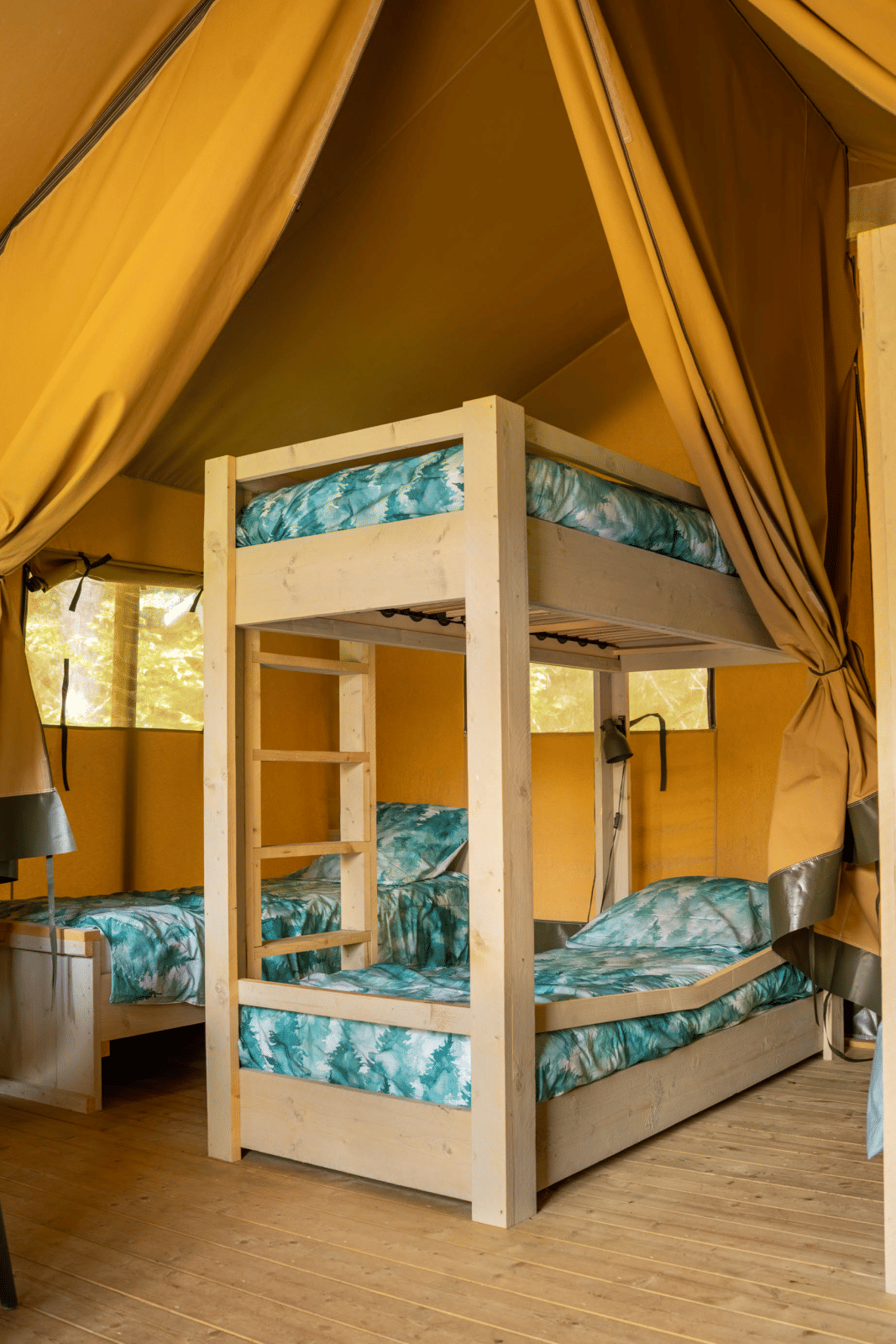 Interieur van een safaritent met stapelbedden bij Flower Camping La Sténiole in Frankrijk.