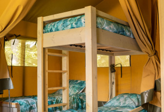 Indretning i en safari telt med køjeseng og enkelt senge på Flower Camping La Sténiole i Frankrig.