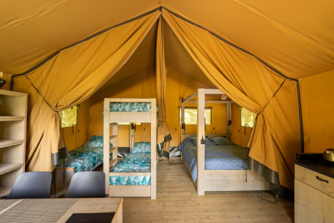Indretning af safari-telt med køjeseng og dobbeltseng på Flower Camping La Sténiole i Frankrig.