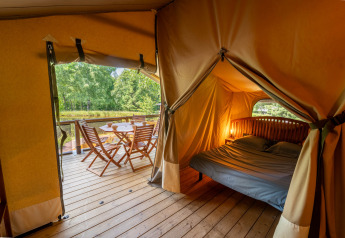 Uitzicht uit de Tente Kenya safaritent met bed en terras bij Flower Camping La Sténiole in Frankrijk.