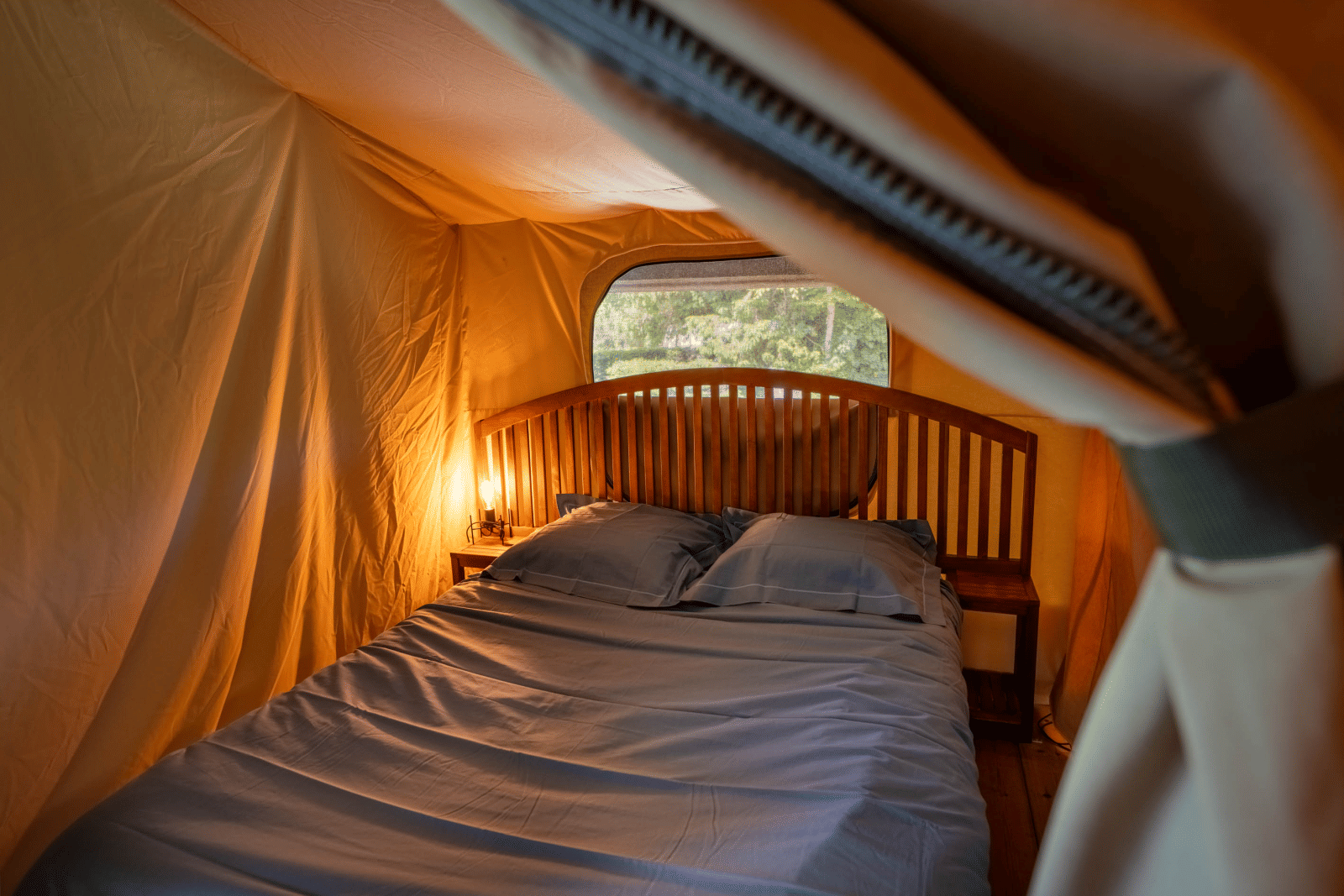 Binnenkant van safaritent Tente Kenya met een comfortabel bed en nachtkastjes op Flower Camping La Sténiole in Frankrijk.
