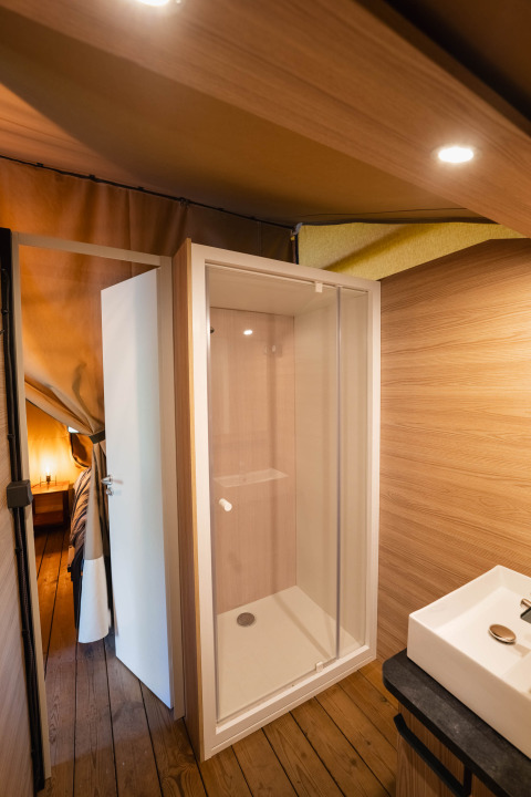 Moderne douche en lavabo in de badkamer van een safaritent bij Flower Camping La Sténiole, Frankrijk.