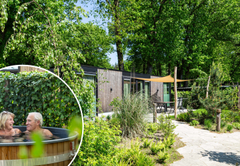 Veluwehoeve Wellness lodge med dejlig have og ældre par, der slapper af i varm hot tub udenfor.