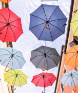 Kleurrijke paraplu's hangen tussen gebouwen in Novigrad, Istrië, Kroatië, van onderaf gezien.