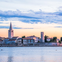 Zonsondergang boven Novigrad, Istrië, Kroatië, met kleurrijke lucht en historische gebouwen aan het water.