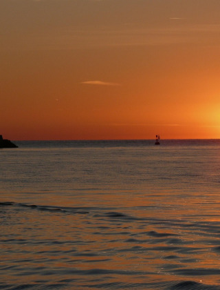 Zonsondergang boven zee nabij Novigrad, Istrië, Kroatië, met een roeiboot op de voorgrond.