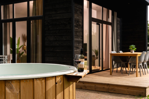 Jacuzzi exterior y terraza en Wellness Boutique baby en Holiday Park Mölke, Países Bajos, con vino.