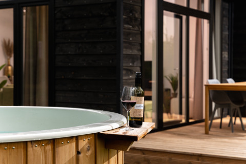 Jacuzzi exterior con una copa y botella de vino tinto en Wellness Boutique baby lodge en Holiday Park Mölke, Países Bajos.