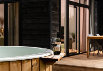 Jacuzzi exterior con una copa y botella de vino tinto en Wellness Boutique baby lodge en Holiday Park Mölke, Países Bajos.