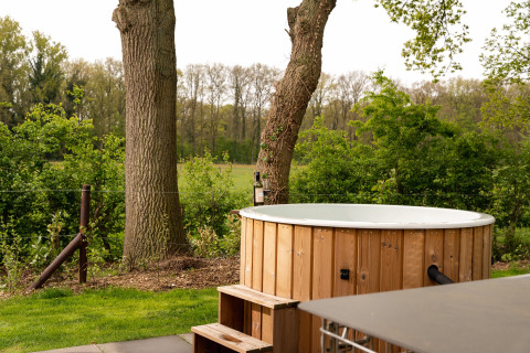 Jacuzzi de madera al aire libre junto a árboles en Wellness Boutique baby, Holiday Park Mölke, Países Bajos.