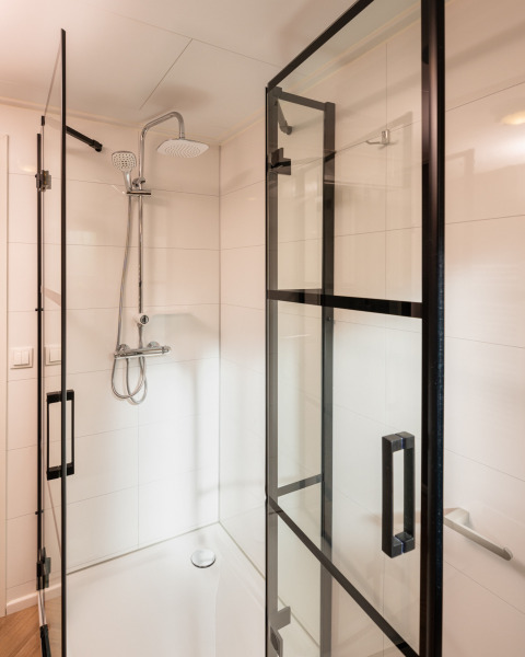 Cabina de ducha moderna con puerta de cristal y ducha de lluvia en Wellness Boutique baby, Holiday Park Mölke, Países Bajos.