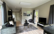 Moderne leefruimte in Just Nature Light-lodge bij De Hooge Veluwe, Nederland, met zetel en tv.