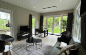 Moderne lodge woonkamer, grote ramen, stijlvolle inrichting en zicht op natuur in De Hooge Veluwe.