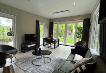 Soggiorno di lodge moderno con finestre ampie, arredo elegante e vista sul verde nei Paesi Bassi.