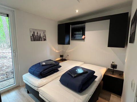 Moderne lodge Just Nature Light ved De Hooge Veluwe, Holland, med to enkeltsenge og skovudsigt.