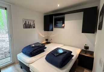 Camera moderna alla lodge Just Nature Light, De Hooge Veluwe, Paesi Bassi, due letti, vista bosco.