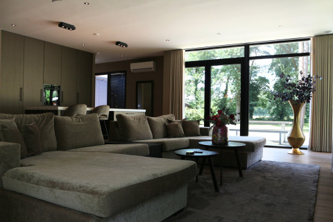 Moderne woonkamer in Forest Lodge Deluxe, Holiday Park BreeBronne, Nederland, met grote ramen.