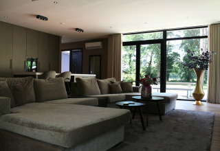 Moderne woonkamer in Forest Lodge Deluxe, Holiday Park BreeBronne, Nederland, met grote ramen.