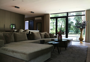 Modern living room in Forest Lodge Deluxe at Holiday Park BreeBronne, Netherlands, with large windows.
