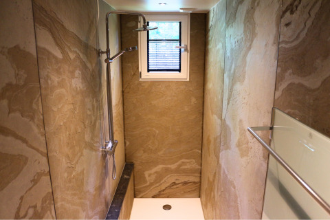 Smalle douche met marmere wanden, klein raam en moderne douchekop in Forest Lodge Deluxe, BreeBronne.