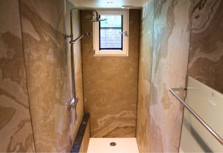 Smalle douche met marmere wanden, klein raam en moderne douchekop in Forest Lodge Deluxe, BreeBronne.