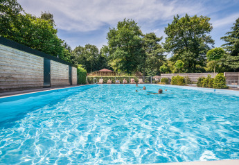 Piscine extérieure dans un hébergement glamping, entourée d'arbres et de vacanciers profitant du soleil.