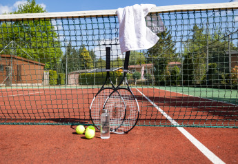 Raquettes, balles, une bouteille d'eau et une serviette sur un terrain de tennis dans un glamping.