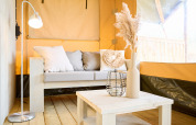 Interior view of a luxury safari tent with sofa, coffee table, and decor at Krieghuusbelten holiday park.